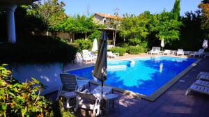een zwembad met stoelen en een parasol ernaast bij Бяла Резидънс - Byala Residence Apart Complex in Byala