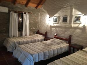 Habitación de hotel con 3 camas y pared de piedra. en Iberá Porá en Colonia Carlos Pellegrini