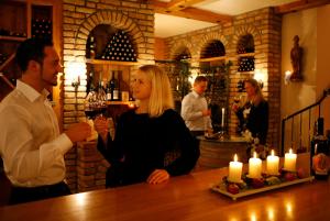 Wienerwaldhof Rieger في Tullnerbach-Lawies: امرأة تقف في حانة مع رجل يحمل كأس النبيذ