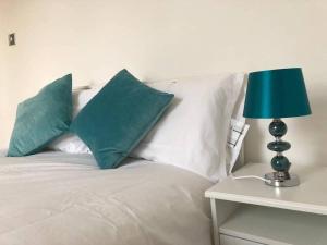 a white bed with green pillows and a blue lamp at Eurostar Budget Rooms - Next to Kings Cross & Eurostar Train Station in London
