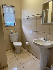 a bathroom with a toilet and a sink at Coral Cottage in Port Shepstone