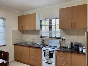 cocina con estufa blanca y armarios de madera en Coral Cottage, en Port Shepstone