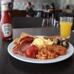 un piatto di prodotti per la colazione con uova, pancetta e una bottiglia di ketchup di Keynes College a Canterbury