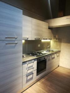 La cuisine est équipée de placards blancs, d'un évier et d'une cuisinière. dans l'établissement Hotel Centrale, à Bologne