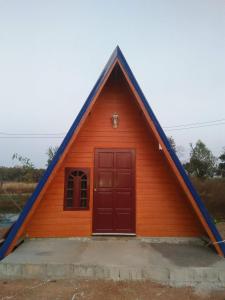 una pequeña casa con un techo puntiagudo en บ้านพักกลางนา en Amphoe Sawang Daen Din