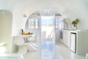 une cuisine blanche avec une table et des chaises blanches dans l'établissement Fira-Cave-Sleeps 13-Parking-Pool-Pet Friendly, à Fira