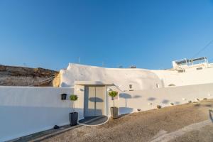 une maison blanche avec une porte bleue et deux plantes dans l'établissement Fira-Cave-Sleeps 13-Parking-Pool-Pet Friendly, à Fira