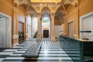um corredor ornamentado com piso xadrez preto e branco em BOTANIQ Castle of Tura - Small Luxury Hotels of the World em Tura