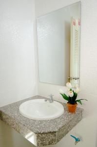 a bathroom sink with a mirror and a vase of flowers at วรรณ เพลส Won Place in Khon Kaen