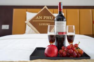 a tray with two glasses of wine and fruit on a bed at An Phú Nguyễn Hoàng Hotel in Hanoi