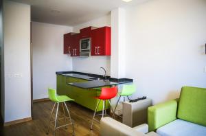 una cocina con armarios y taburetes verdes y rojos en Atlantic Apartments en Las Palmas de Gran Canaria