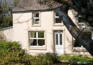 una casa bianca con porta bianca e finestre di Stone Hall Mill Cottage, Welsh Hook a Saint Lawrence