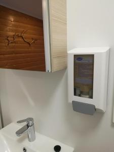 - un lavabo dans la salle de bains avec un distributeur de savon sur le mur dans l'établissement Lapphaugen Turiststasjon, à Tennevoll