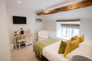 a bedroom with a bed and a desk and a television at The Red Lion at Hellidon in Daventry