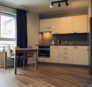 a kitchen with white cabinets and a table with chairs at LOFT Aprtament in Piła