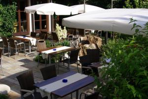 eine Außenterrasse mit Tischen, Stühlen und Sonnenschirmen in der Unterkunft Flair Hotel Dobrachtal in Kulmbach