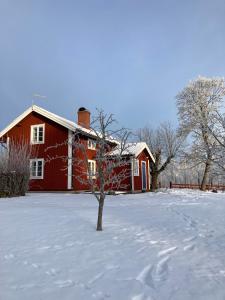 une maison rouge avec de la neige au sol dans l'établissement Stuga Linnebråten, à Värnamo