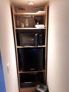 a book shelf with a microwave and a tv at SPA privatif Love room, Le Hammam et Bulles, chez Nuits Chartraines in Chartres +22 photos