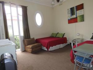 um quarto com uma cama, uma cadeira e uma janela em Hotel Baleares em Santiago