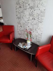 a room with two red chairs and a table with flowers at Pensiunea Caramell in Cluj-Napoca