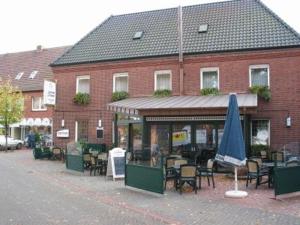 a building with tables and chairs and a blue umbrella at Hotel Franke in Alstätte