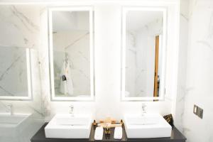 two sinks in a white bathroom with two mirrors at Ramë Hotel Boutique in Guadalajara