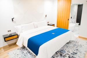1 Schlafzimmer mit einem blauen und weißen Bett und einem Badezimmer in der Unterkunft Ramë Hotel Boutique in Guadalajara