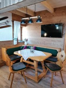 ein Esszimmer mit einem Tisch und Stühlen sowie einem TV in der Unterkunft Greenheart Aussee in Obersdorf