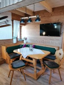 jadalnia ze stołem i krzesłami oraz telewizorem w obiekcie Greenheart Aussee w mieście Obersdorf