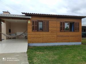 ein kleines Haus mit einer Hängematte davor in der Unterkunft Casa de Praia. Lugar sossegado para recarregar as energias. in Passo de Torres