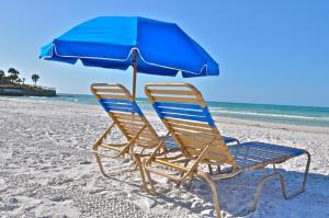 two beach chairs and an umbrella on the beach at Twin Palms at Siesta in Siesta Key