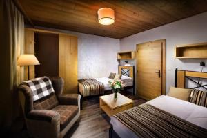 a hotel room with a bedroom with a bed and a chair at Chalet Jasná Wellness Apartment Maxim jacuzzi & sauna in Demanovska Dolina