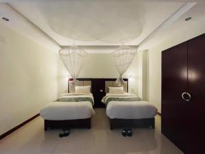 two beds in a room with white walls and ceilings at Winn Hotel - Bahir Dar in Bahir Dar