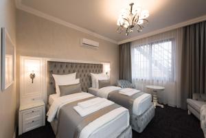 クラスノダールにあるBoutique-hotel Stolicaのベッド2台とシャンデリアが備わるホテルルームです。