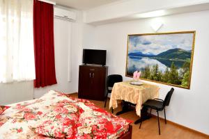 a bedroom with a bed and a table and a painting at Casa Simescu I in Caransebeş