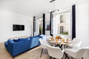 uma sala de estar com um sofá azul e cadeiras brancas em Villa Californie YourHostHelper em Cannes