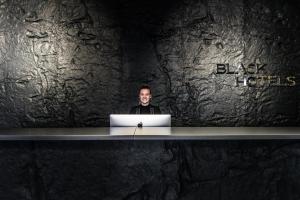 een man aan een bureau met een laptop bij Black Hotels Köln in Keulen