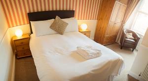 1 dormitorio con 1 cama blanca grande y 2 lámparas en Elder York Guest House, en Edimburgo