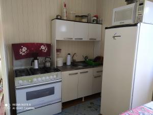 eine kleine Küche mit einem Kühlschrank und einem Herd in der Unterkunft Casa de Praia. Lugar sossegado para recarregar as energias. in Passo de Torres