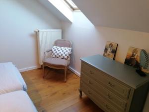 a bedroom with a dresser and a chair next to a bed at L'autre rive de la Tourelle in Ways