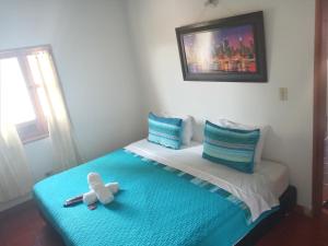 a teddy bear sitting on top of a bed at Hostal El Pino in Villa de Leyva