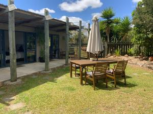a wooden table with an umbrella and two chairs at A Cut Above Lodge - The Gateway to the Bay of Islands in Kerikeri