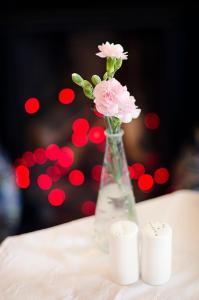 Elder York Guest House في إدنبرة: مزهرية مع الزهور الزهرية على طاولة مع الشموع