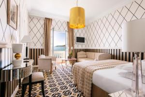 a hotel room with a bed and a living room at Hôtel Belles Rives in Juan-les-Pins