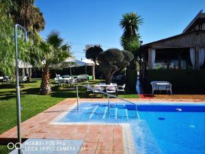a swimming pool in a yard with trees and a house at Hostal Al-Andalus in La Guijarrosa