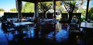 un restaurante con mesas, sillas y palmeras en Hostal Al-Andalus, en La Guijarrosa