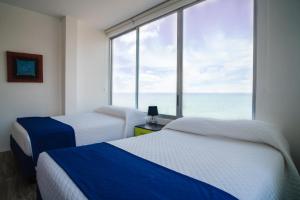2 Betten in einem Zimmer mit einem großen Fenster in der Unterkunft Exclusivo Penthouse frente al mar con acceso a la playa - Club Privado en Manta in Manta