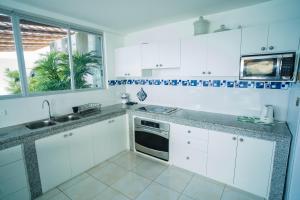 eine Küche mit weißen Schränken, einem Waschbecken und einem Fenster in der Unterkunft Exclusivo Penthouse frente al mar con acceso a la playa - Club Privado en Manta in Manta