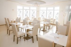 a restaurant with white tables and chairs and windows at Hotel Court Wellness&Spa in Kędzierzyn-Koźle