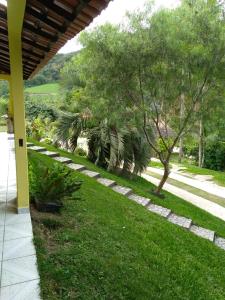 a garden with grass and trees and a pathway at Casa com Flores in Pedra Azul
